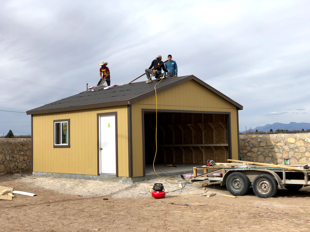 Professionals building a large yellow shed in El Paso.